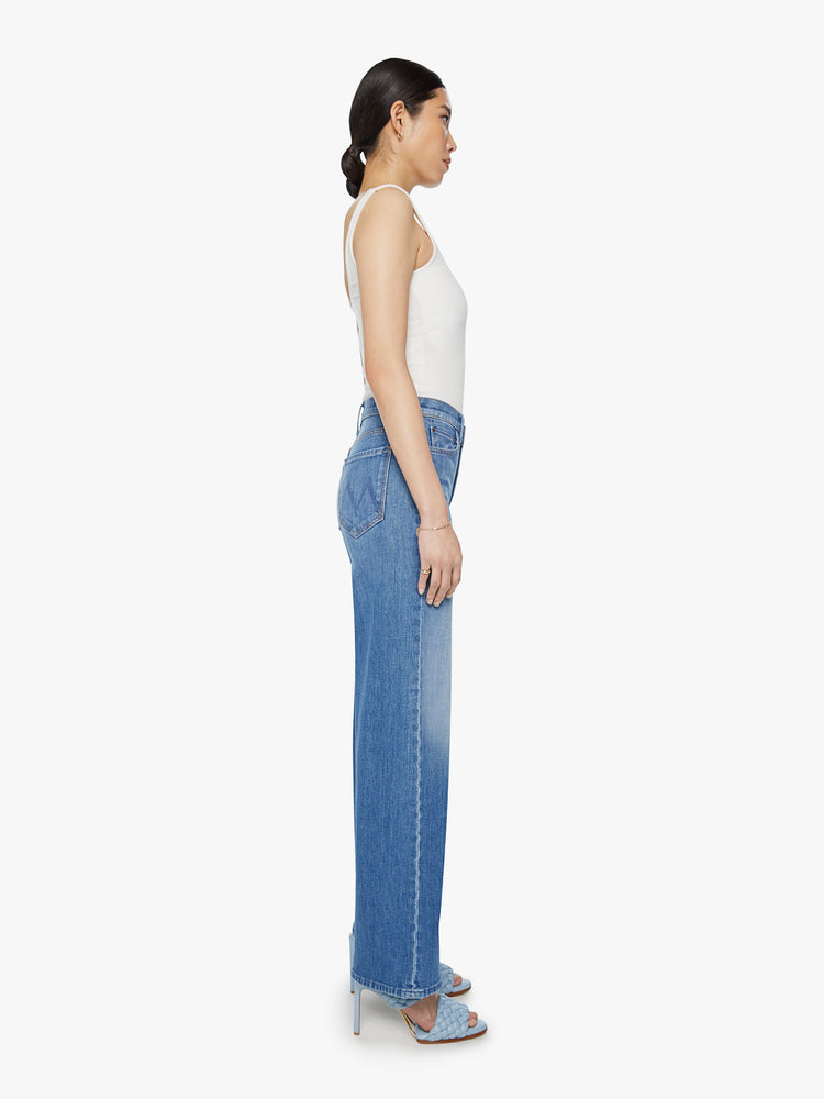Side view of a woman wide leg pants with a high rise, long 32-inch inseam and a clean hem in a med blue wash.