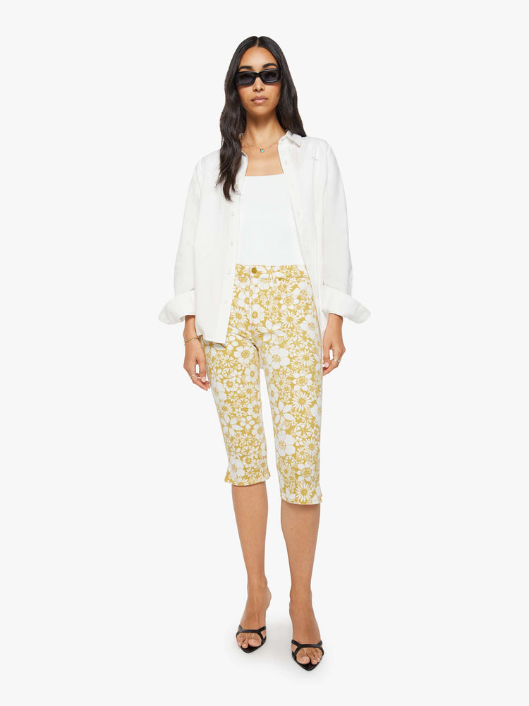 Front view of a woman in a off white with golden yellow floral print high-waisted pants with a skinny leg, zip fly and a capri-length inseam.