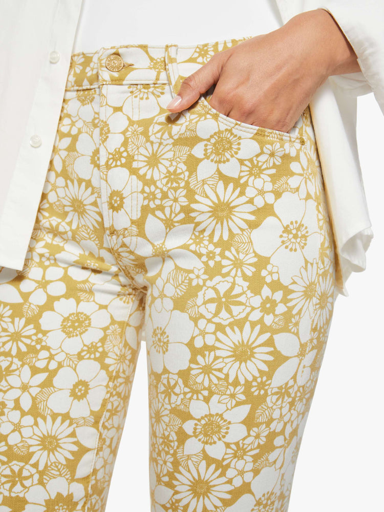 Close up view of a woman in a off white with golden yellow floral print high-waisted pants with a skinny leg, zip fly and a capri-length inseam.