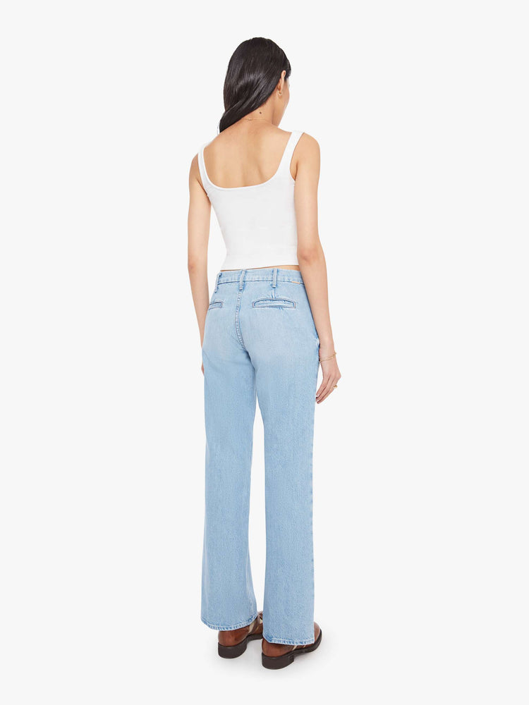 Back view of a woman in a light blue mid-rise  bootcut with a zip fly, slit pockets, looser leg and a long 32-inch inseam with a clean hem. 