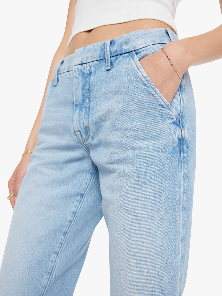 Close uop viw of a woman in a light blue mid-rise  bootcut with a zip fly, slit pockets, looser leg and a long 32-inch inseam with a clean hem. 