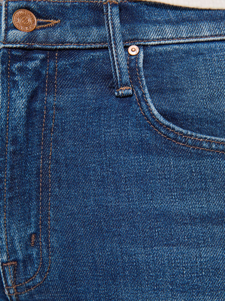 Swatch view of a woman in a md blue high-waisted bootcut is cropped at the ankle with a frayed step-hem.
