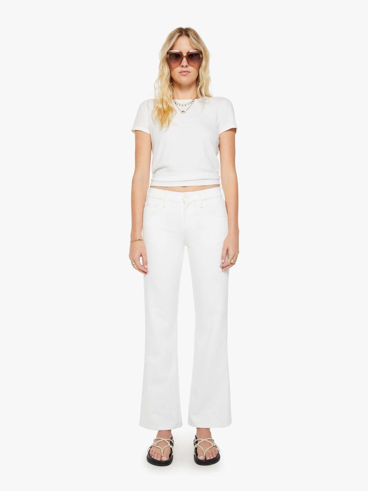 Front view of a woman in a white mid-rise bootcut with a zip fly, looser leg and a long 31-inch inseam with a clean hem.