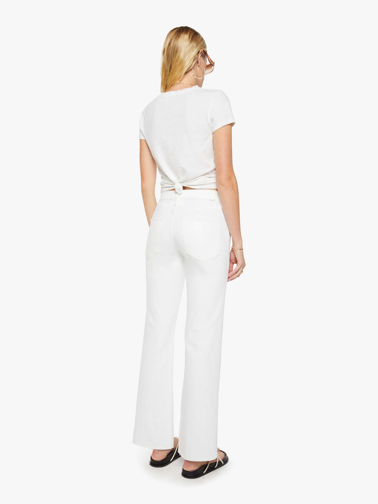 Back view of a woman in a white mid-rise bootcut with a zip fly, looser leg and a long 31-inch inseam with a clean hem.