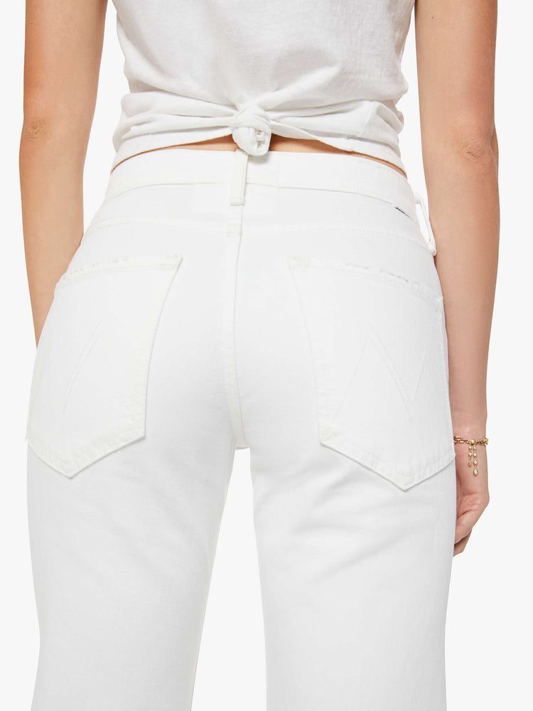Back view of a woman in a white mid-rise bootcut with a zip fly, looser leg and a long 31-inch inseam with a clean hem.