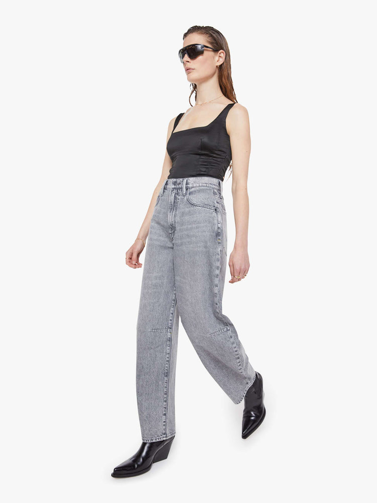 Walking view of a woman in a super high-waisted jeans with a zip fly, curved, tapered leg and an ankle-length inseam with a clean hem.