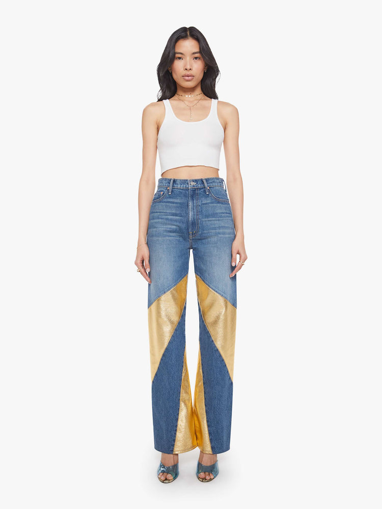 Front view of a woman in a super high-waisted bootcut jeans with a zip fly and a long 34-inch inseam with a clean hem in a mid blue with gold spiral patches.