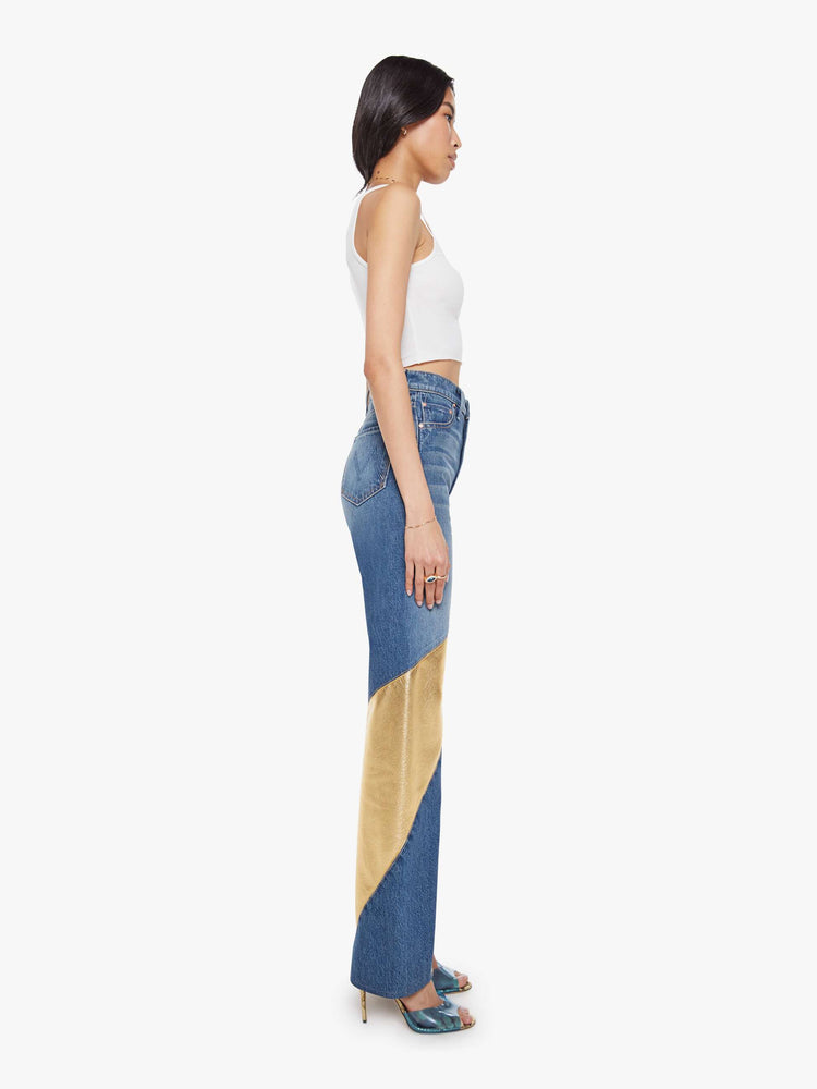 Side view of a woman in a super high-waisted bootcut jeans with a zip fly and a long 34-inch inseam with a clean hem in a mid blue with gold spiral patches.