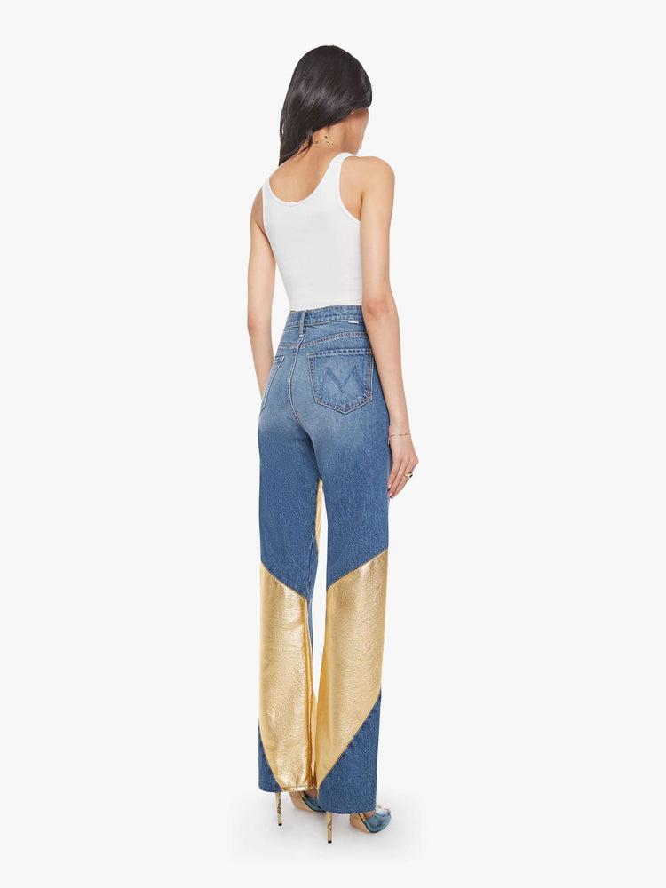 Back view of a woman in a super high-waisted bootcut jeans with a zip fly and a long 34-inch inseam with a clean hem in a mid blue with gold spiral patches.