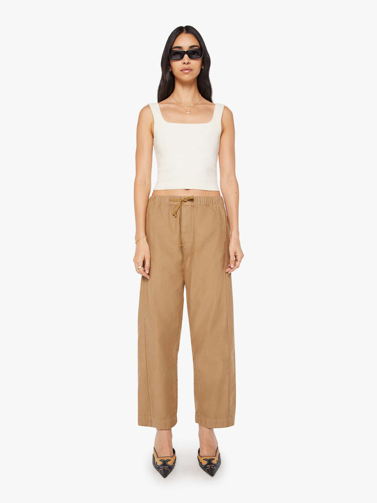 Front view of a woman in a super high-waisted khaki pants with a drawstring waistband, wide, curved leg, an ankle-length inseam and a clean hem.