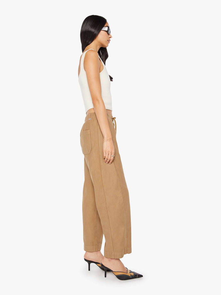 Side view of a woman in a super high-waisted khaki pants with a drawstring waistband, wide, curved leg, an ankle-length inseam and a clean hem.