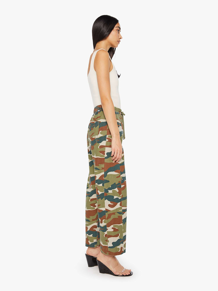 Side view of a woman in a classic camouflage super high-waisted pants with a drawstring waistband, wide, curved leg, an ankle-length inseam and a clean hem. 