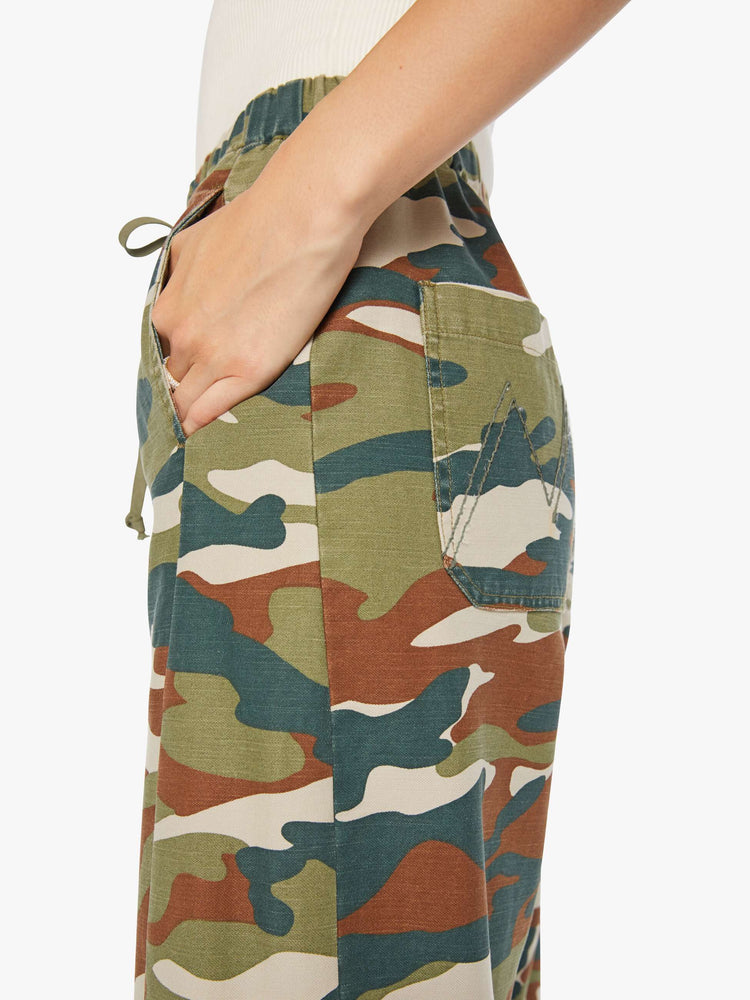 Close up view of a woman in a classic camouflage super high-waisted pants with a drawstring waistband, wide, curved leg, an ankle-length inseam and a clean hem. 
