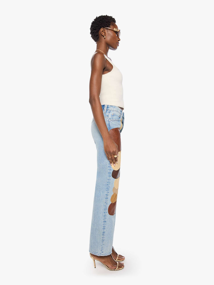 Side view of a woman in a light blue with faux leather and suede patches on the front jean with a high-rise straight-leg with a zip fly, 32-inch inseam and a clean hem
