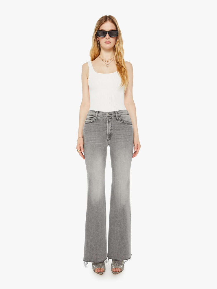 Front view of a woman in a light grey high rise flare  with a long 32-inch inseam, zip fly and a frayed hem