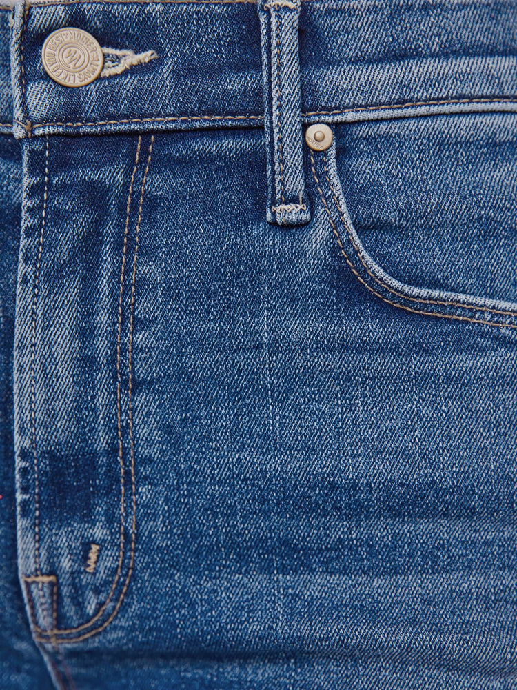 Swatch view of a woman in a medium blue high-rise flare with a zip fly, long 32-inch inseam and a frayed hem.