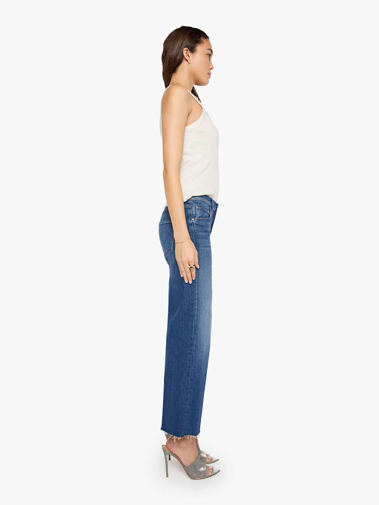 Side view of a woman in a mid-rise jeans with a wide straight leg, zip fly and a 28.25-inch inseam with a frayed hem.