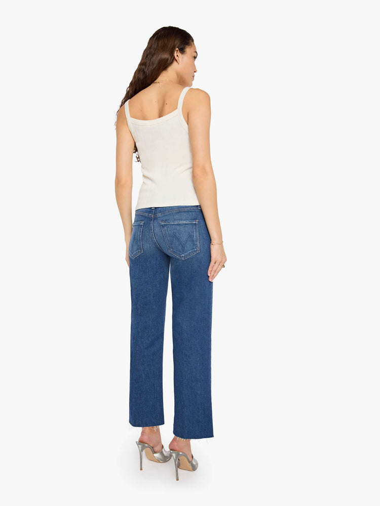 Back view of a woman in a mid-rise jeans with a wide straight leg, zip fly and a 28.25-inch inseam with a frayed hem.