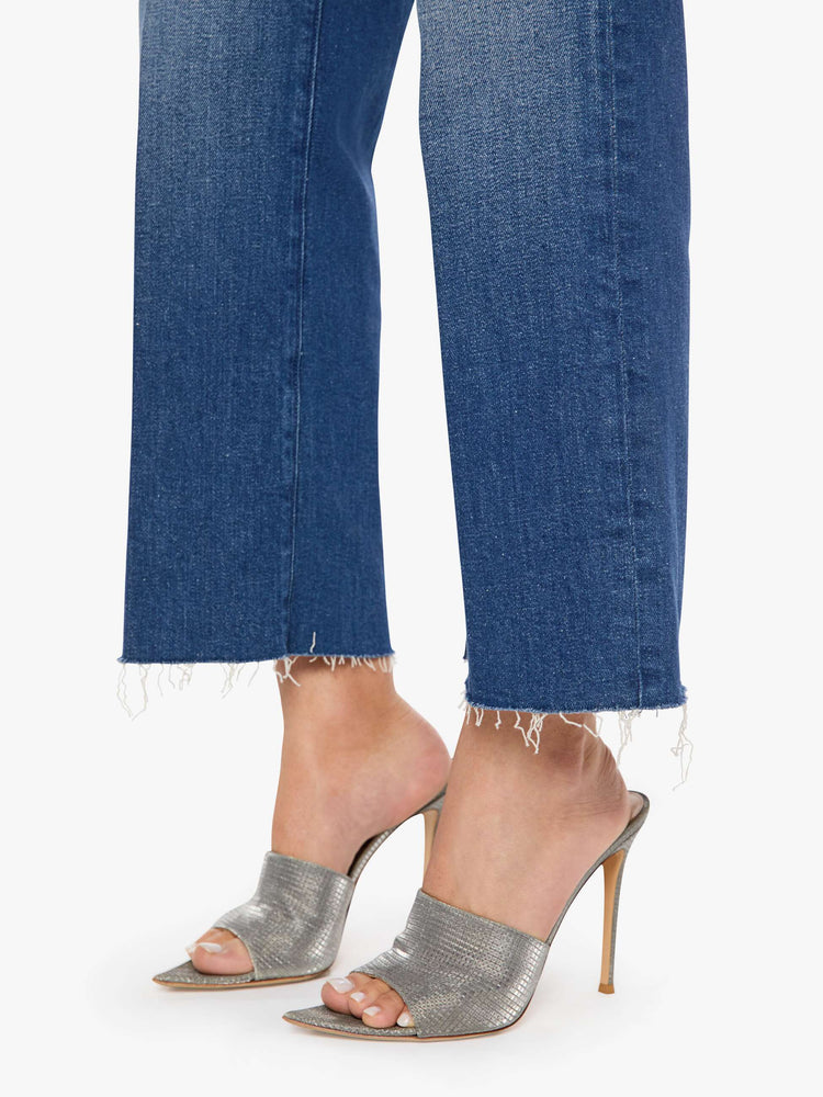 Hem view of a woman in a mid-rise jeans with a wide straight leg, zip fly and a 28.25-inch inseam with a frayed hem.