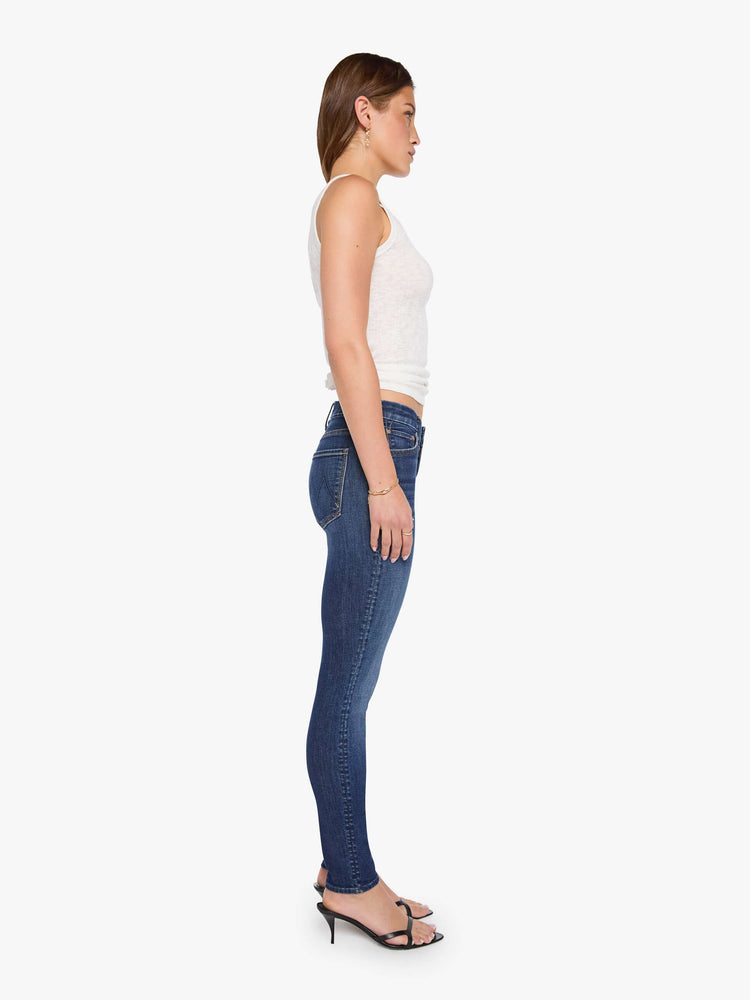 Side view of a woman in a dark blue skinny has a low rise with a zip fly, 29-inch inseam and a clean hem.