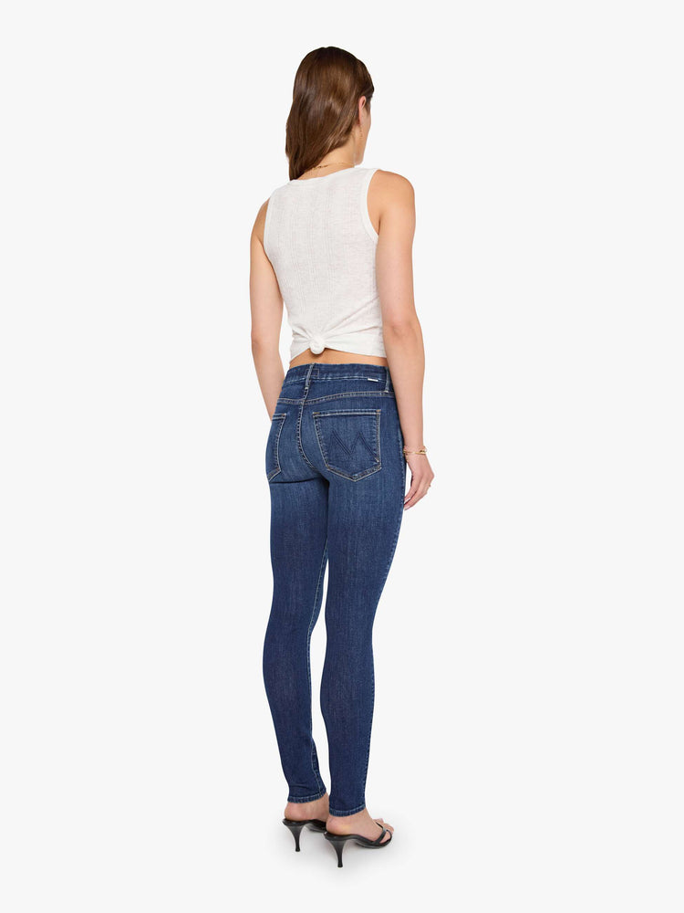 Back view of a woman in a dark blue skinny has a low rise with a zip fly, 29-inch inseam and a clean hem.