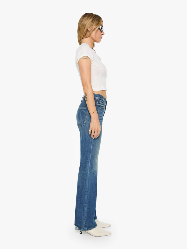 Side view of a woman in a  straight leg with a bit of a kick, the jean features a mid rise, full-length inseam and clean hem in a classic blue.