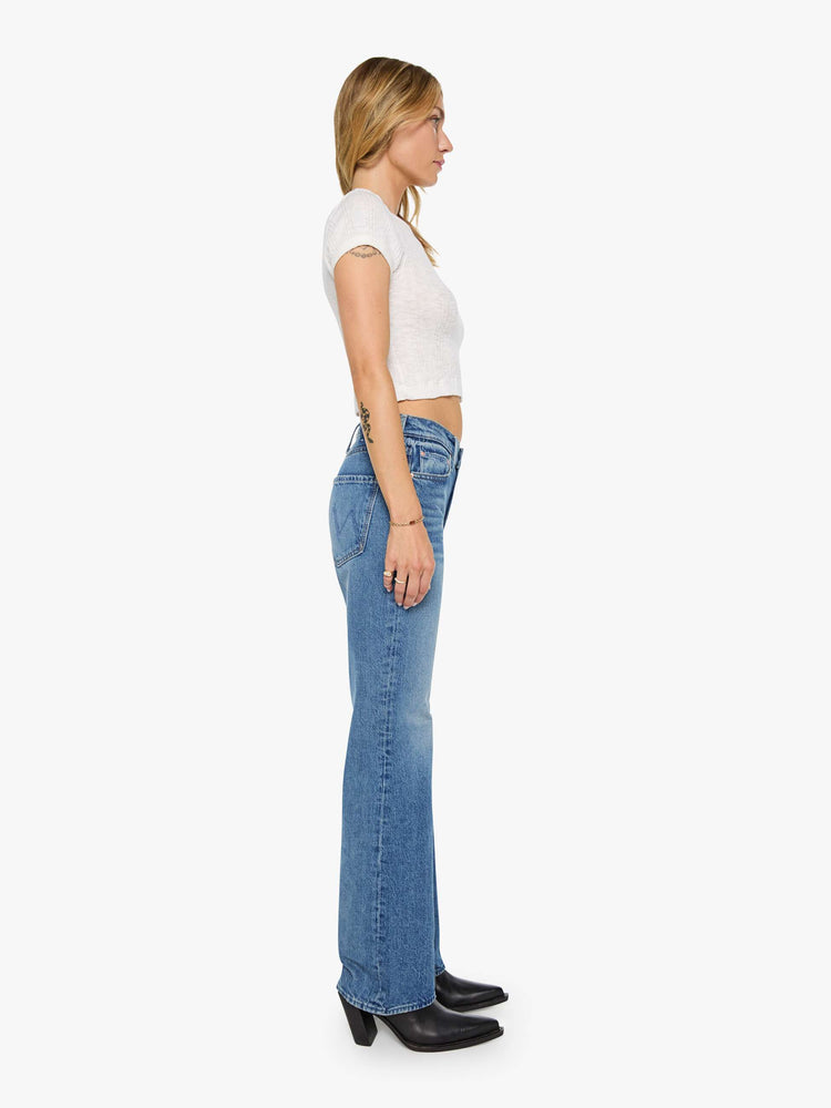 Side view of a woman in a  straight leg with a bit of a kick, the jean features a mid rise, full-length inseam and clean hem in med blue wash.