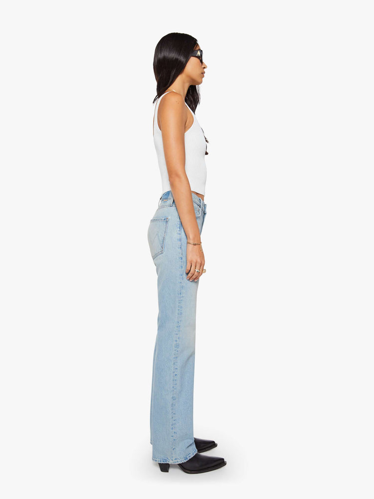 Side view of a woman in a light blue straight leg with a bit of a kick, the jean features a mid rise, full-length inseam, distressed hem and relaxed fit.