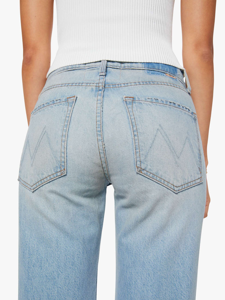 Back close up view of a woman in a light blue straight leg with a bit of a kick, the jean features a mid rise, full-length inseam, distressed hem and relaxed fit.