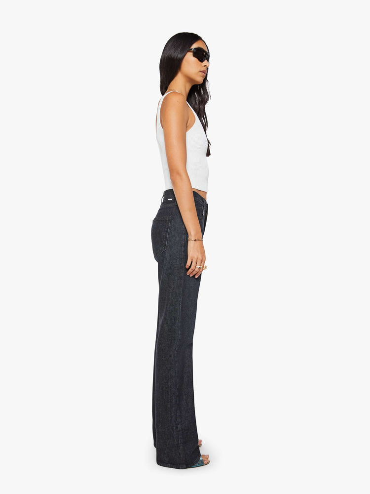 Side view of a woman in black straight leg with a bit of a kick, the jean features a mid rise, full-length inseam, distressed hem and relaxed fit.