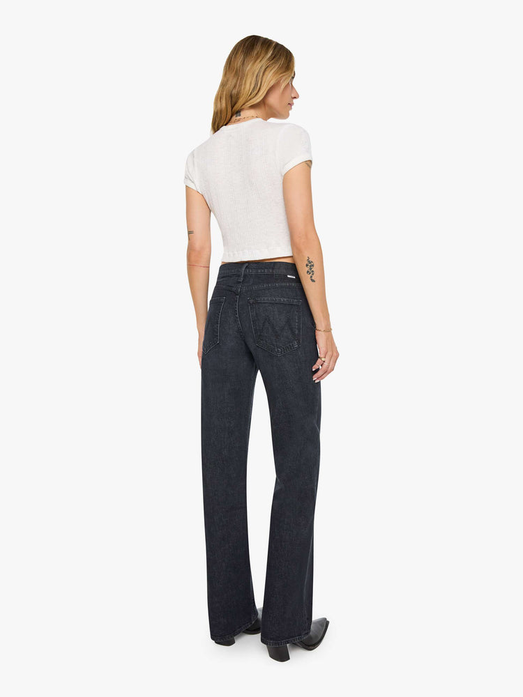 Back view of a woman in black straight leg with a bit of a kick, the jean features a mid rise, full-length inseam, distressed hem and relaxed fit.