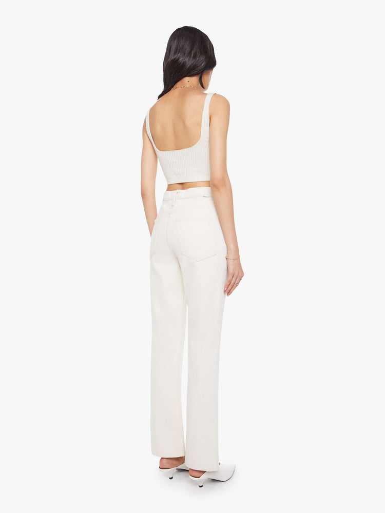 Back view of a woman in ivory jean designed to sit on the hips with a slouchy fit with a flared leg, zip fly, a 32.75-inch inseam and a super high rise with a slightly dropped crotch.