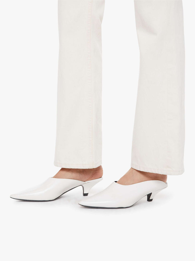 Hem close up view of a woman in ivory jean designed to sit on the hips with a slouchy fit with a flared leg, zip fly, a 32.75-inch inseam and a super high rise with a slightly dropped crotch.