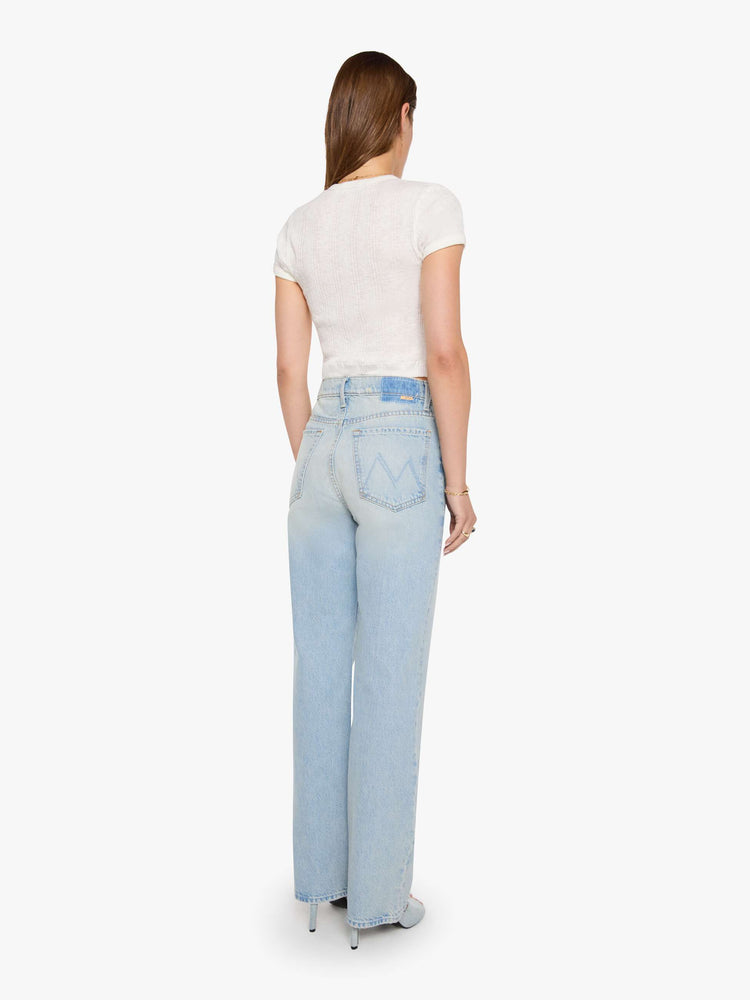 Back view of a woman in a light blue high-rise jeans with a wide straight leg, zip fly and long 31-inch inseam with a clean hem. 