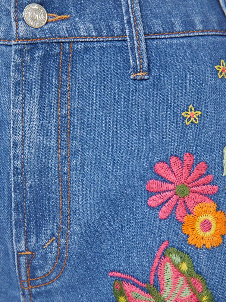 Swatch view of a woman in a med blue with embroidery flowers  wide leg jeans with a high rise, zip fly, long inseam and a clean hem.