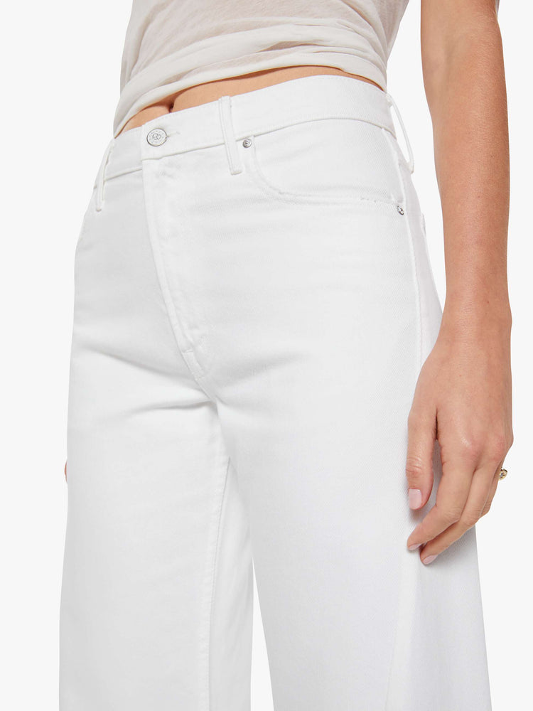 Close up view of a woman in a white high-rise pants have a zip fly, loose wide leg with a curved outer seam and a 32-inch inseam with a clean hem.