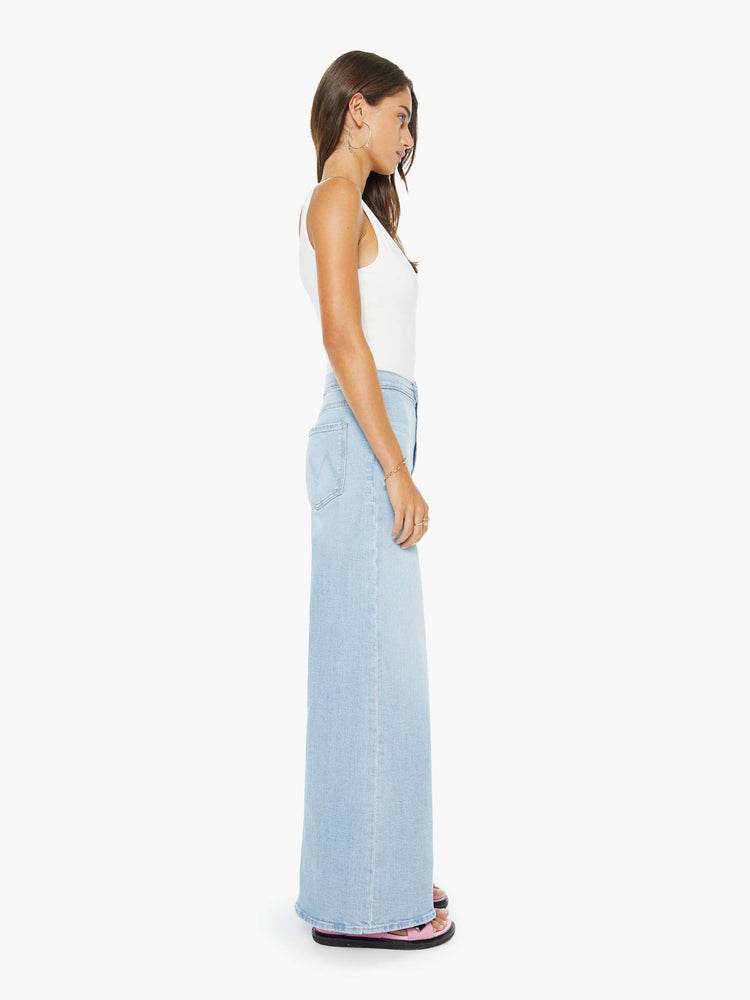 Side view of a woman in a light blue high rise wide leg jean, zip fly, tabbed waistband, long 31-inch inseam and a clean hem.