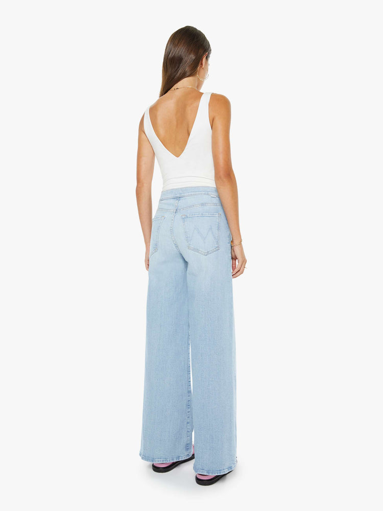 Back view of a woman in a light blue high rise wide leg jean, zip fly, tabbed waistband, long 31-inch inseam and a clean hem.
