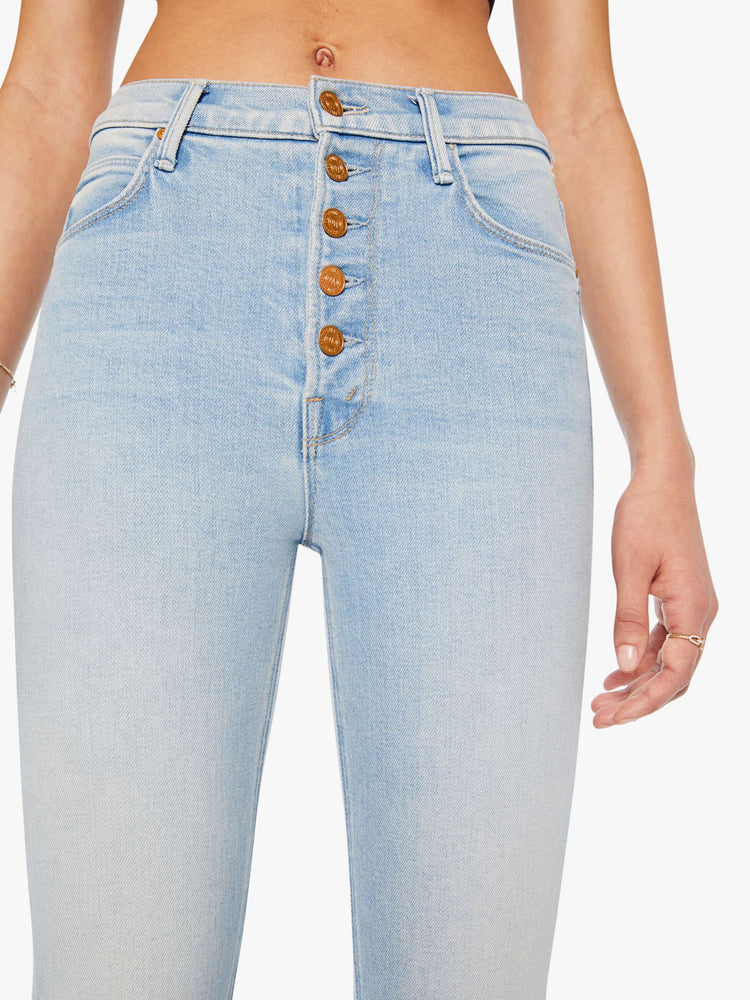 Front close up view of a woman in a light blue  high-rise straight leg has an exposed button fly and a clean ankle-length inseam. 