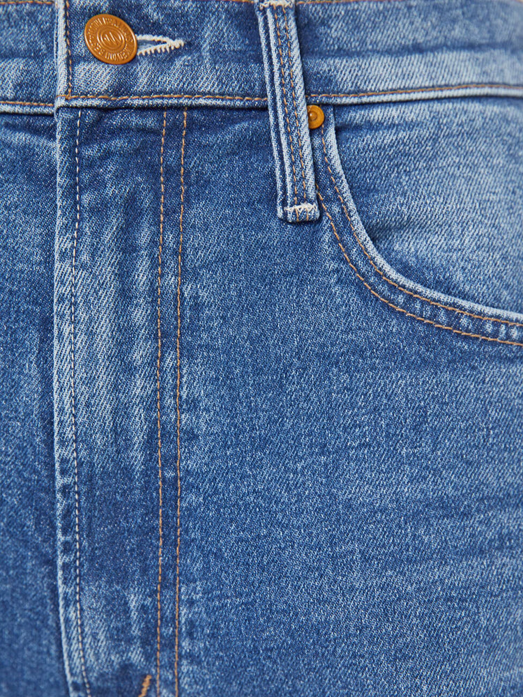 Swatch view of a woman in a med blue high-rise bootcut with a zip fly, looser leg and a long 32-inch inseam with a clean hem.