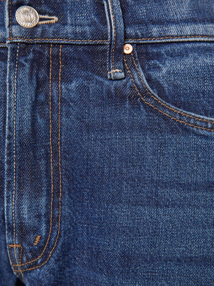 Swatch view of a woman in a dark blue mid-rise jeans designed to sit lower on the hips with a full barrel leg, zip fly, 28.25-inch inseam and a frayed hem.