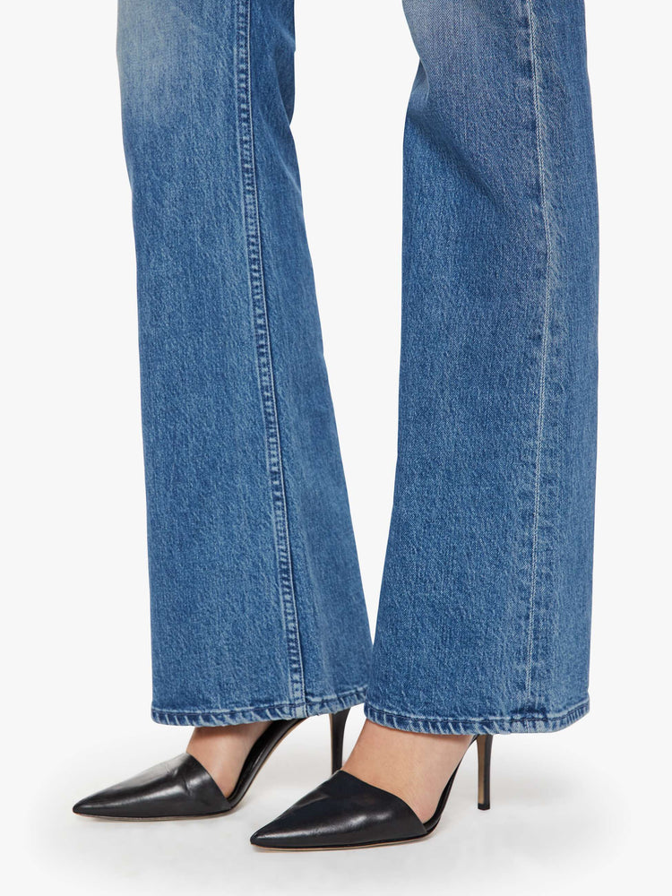 Hem view of a woman in a mid blue mid-rise jeans with a flared leg, zip fly and a long 34-inch inseam with a clean hem.