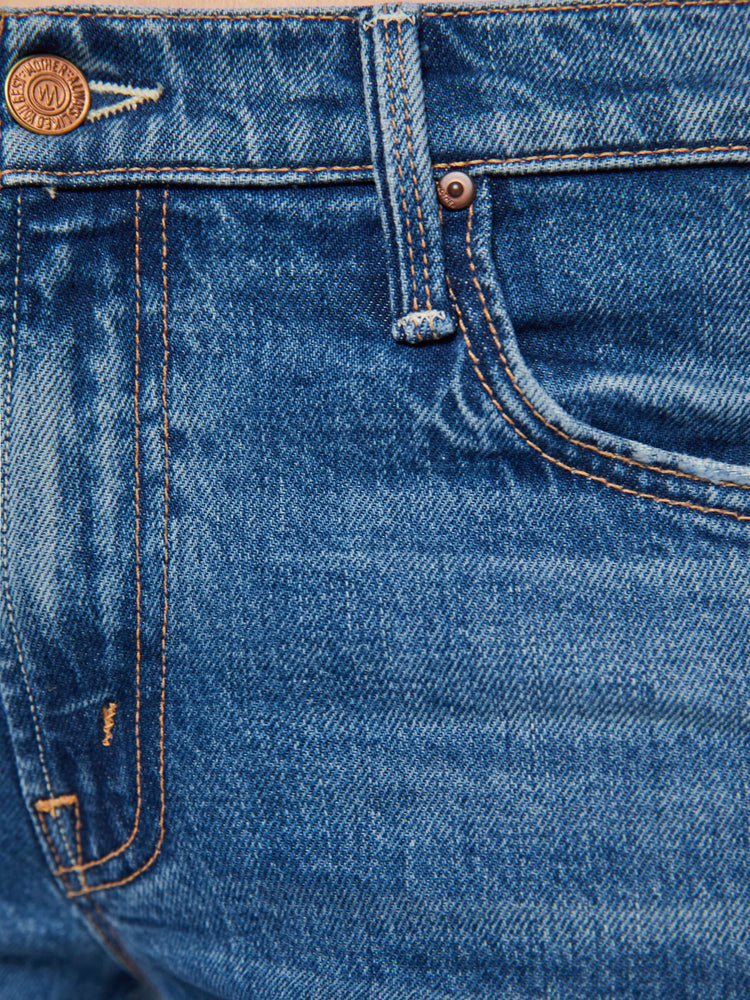 Swatch view of a woman in a mid blue mid-rise jeans with a flared leg, zip fly and a long 34-inch inseam with a clean hem.