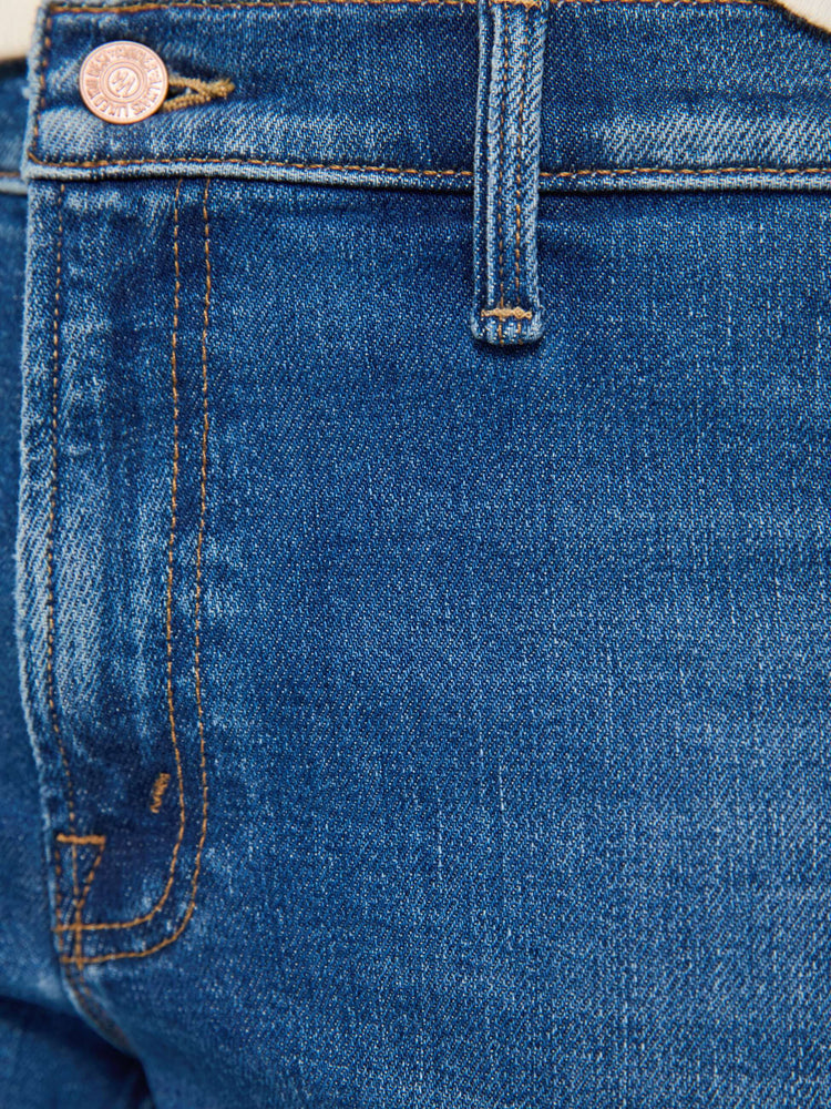 Swatch view of a woman in a med blue high-rise flare has a zip fly, patch pockets on the thighs, a curved seam across the back, 31-inch inseam and a clean hem. 
