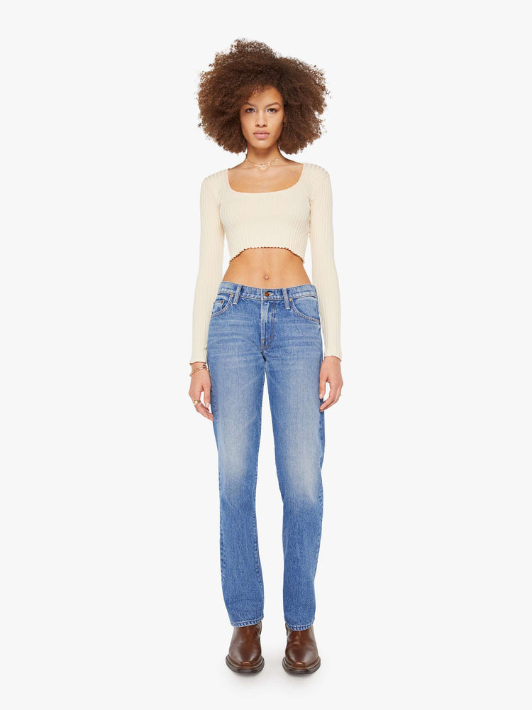Front view a woman in a lower-rise mid blue jeans that have a narrow straight-leg and a long 32-inch inseam with a clean hem. 