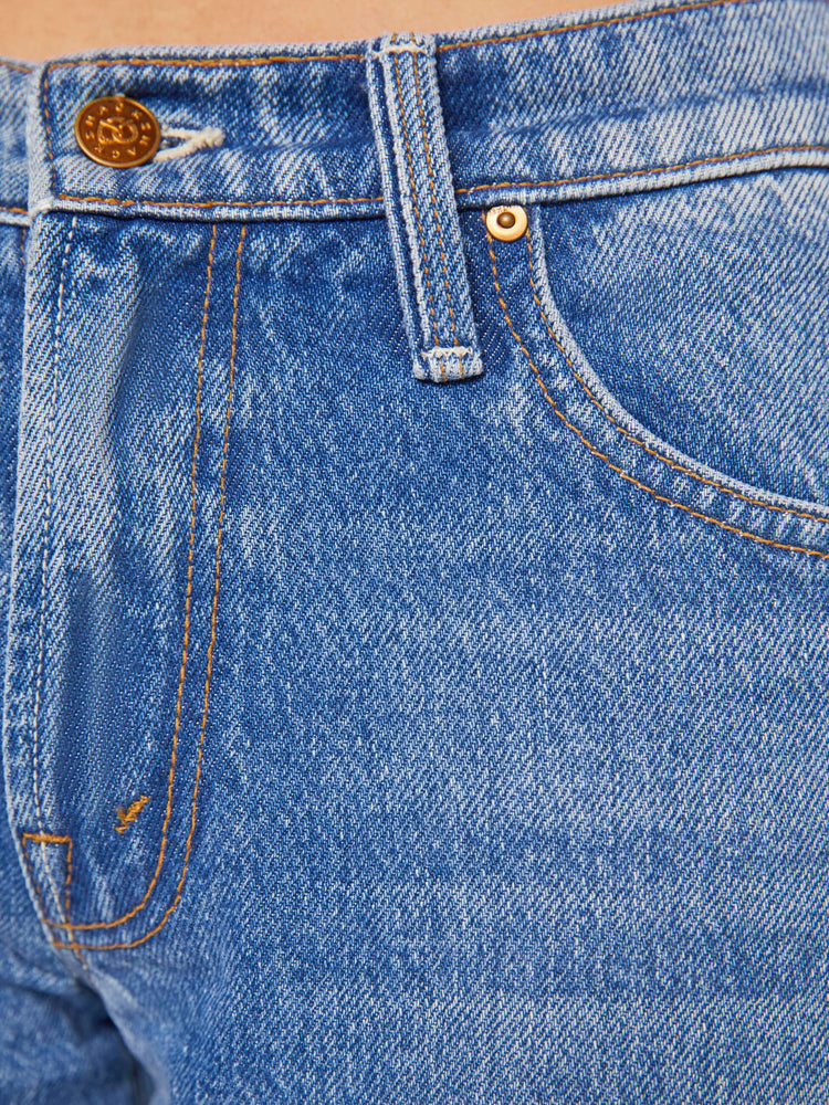 Swatch view a woman in a lower-rise mid blue jeans that have a narrow straight-leg and a long 32-inch inseam with a clean hem. 