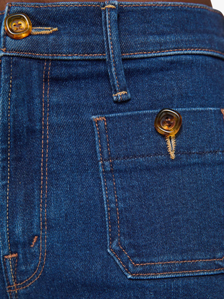 Swatch view of a woman in a dark blue high-rise flare with a zip fly, patch pockets that button, a long 34-inch inseam and a clean hem.
