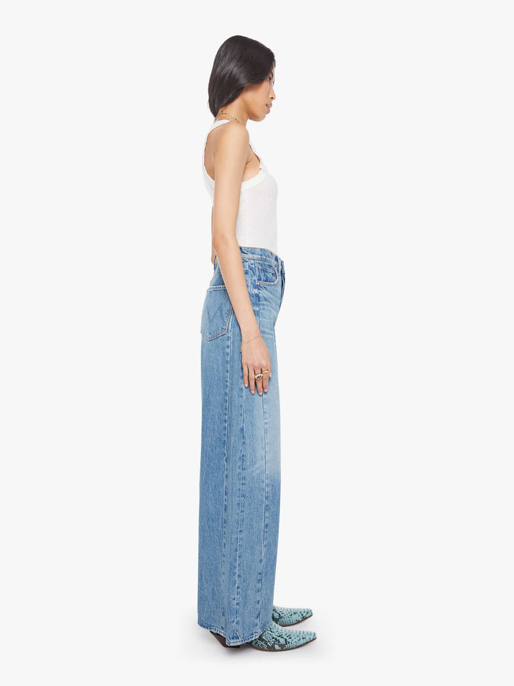 Side view of a woman in a med blue super high-waisted barrel-leg jeans with a long 32-inch inseam, a button fly, inset panels on the outer seams, a clean hem and relaxed fit.