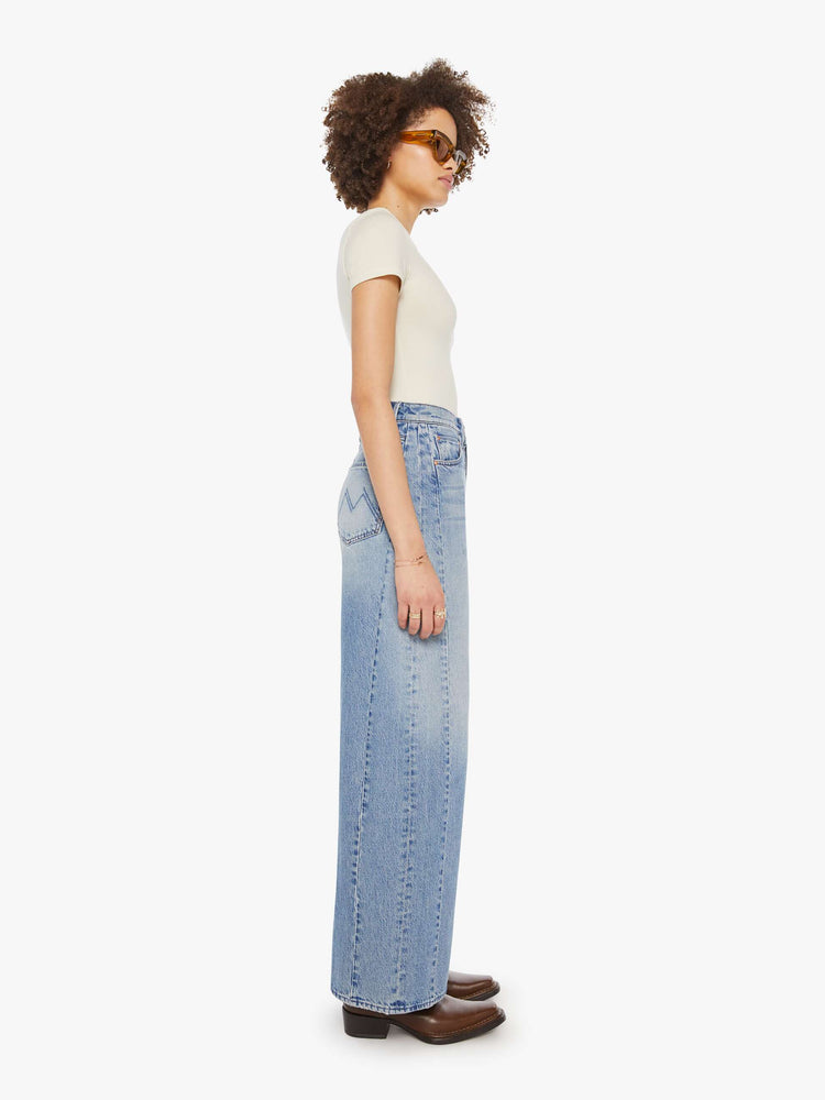 Side view of a woman in a light blue super high-waisted barrel-leg jeans with a long 31-inch inseam, button fly, clean hem and relaxed fit.