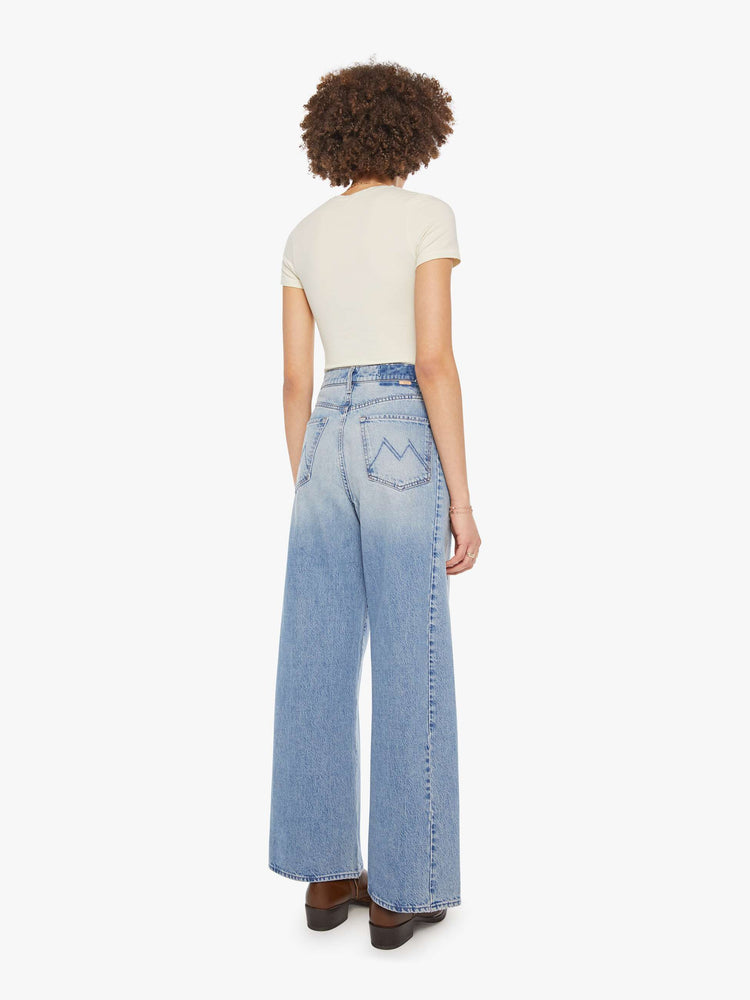 Back view of a woman in a light blue super high-waisted barrel-leg jeans with a long 31-inch inseam, button fly, clean hem and relaxed fit.